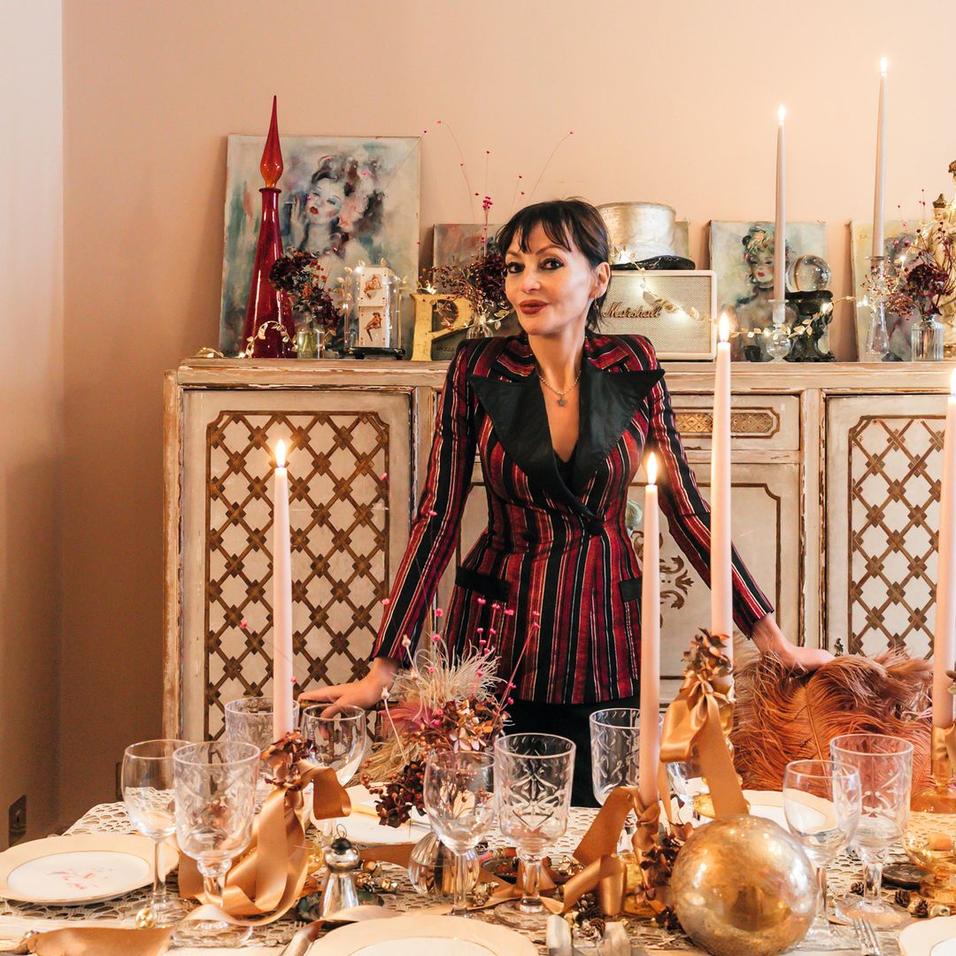 Pearl Lowe, con un traje rojo y negro, está de pie junto a una mesa elegantemente decorada.