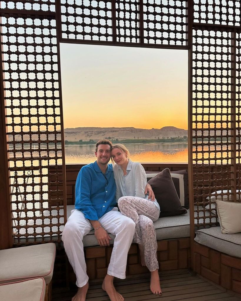 Plano entero de Sophie Turner y Peregrine Pearson abrazados en un sofá al aire libre