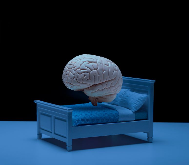 Modelo de cerebro humano flotando sobre una cama en una habitación oscura.
