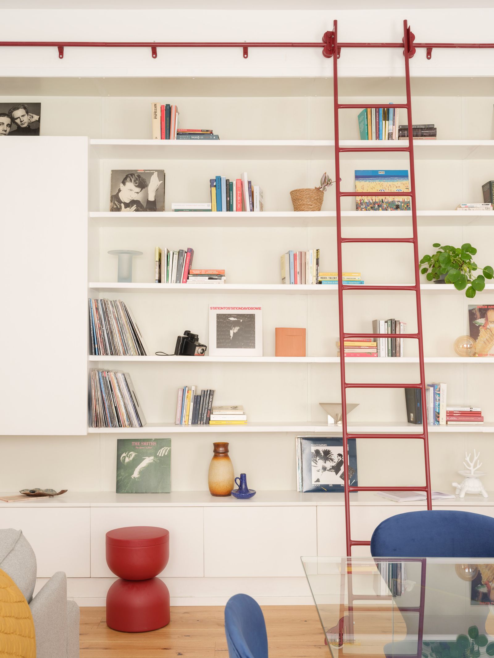 Salón con estantería blanca y escaleras rojas