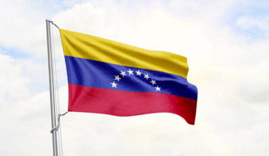 Una bandera de Venezuela ondea frente a un cielo con algunas nubes.