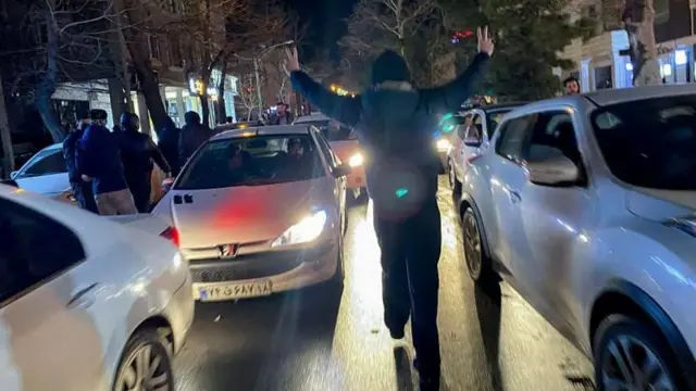 Un manifestante en medio de dos coches. 