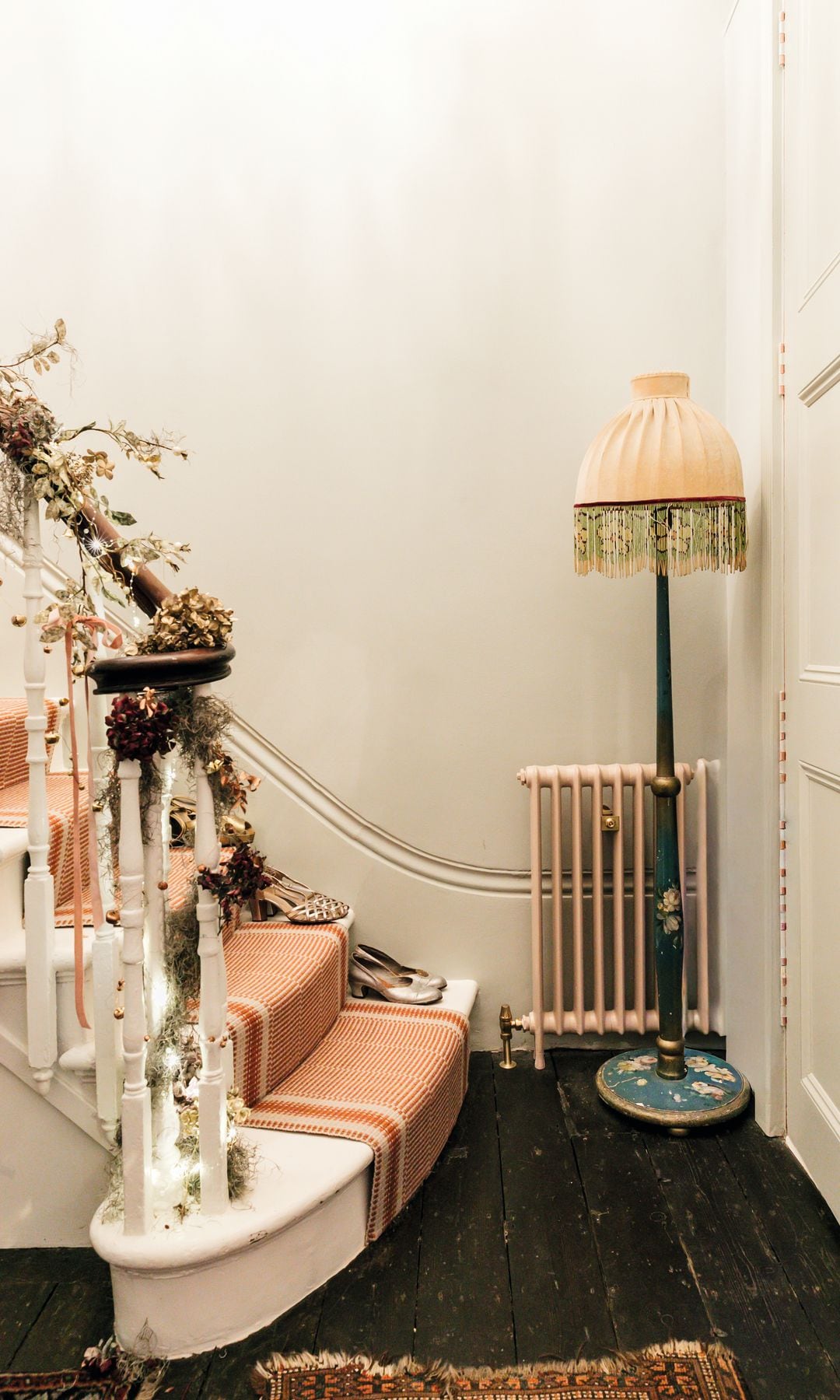 Escalera decorada con luces y plantas, junto a una lámpara y radiador.
