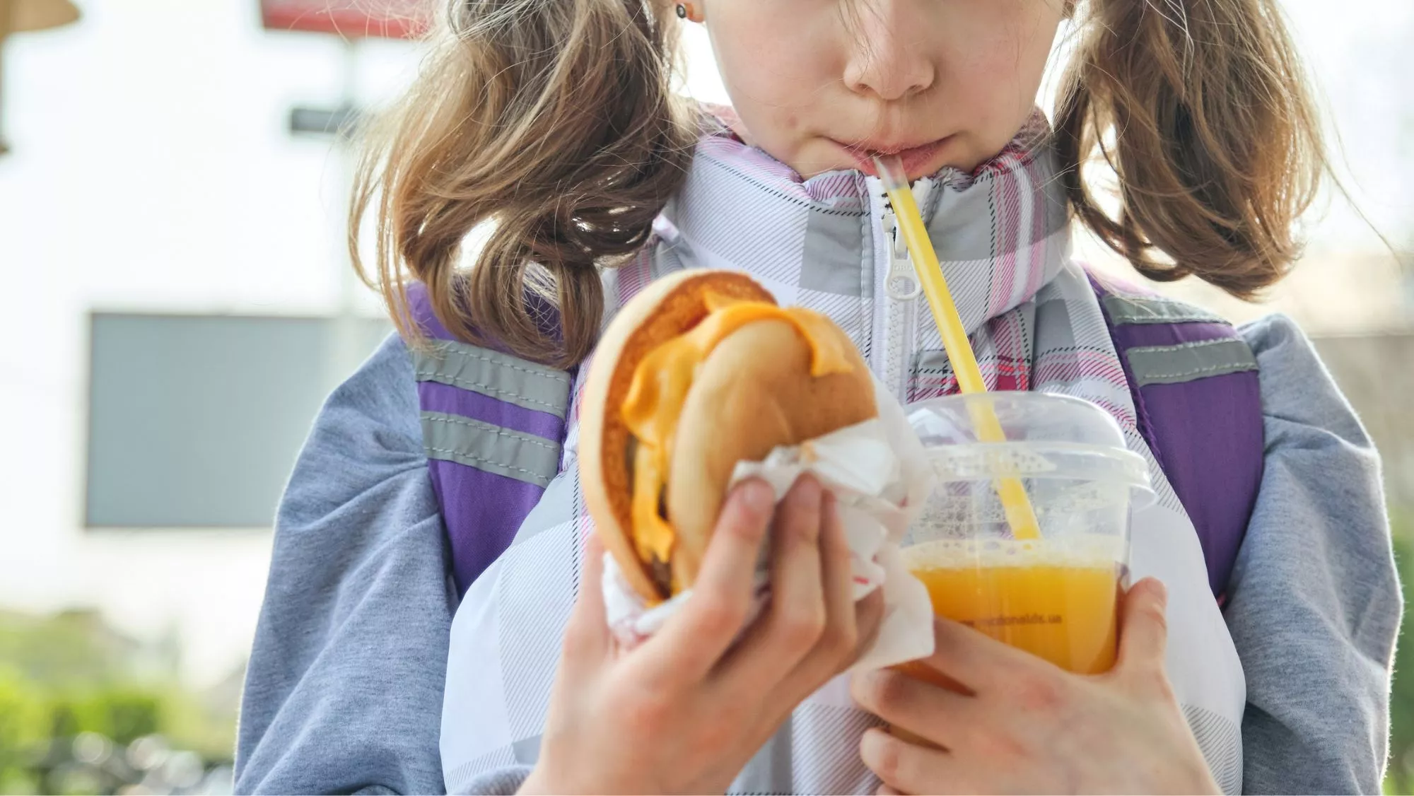 Niña comiendo 'Fast food' o 'comida basura' / Canva