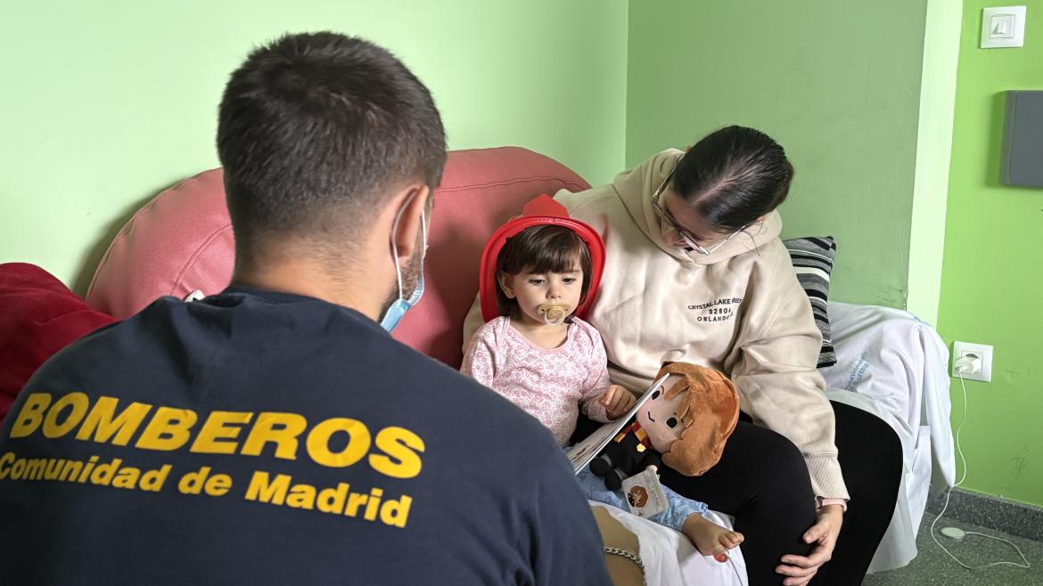 Bombero entregando regalo a niña ingresada