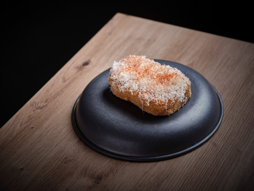 a piece of food garnished with grated texture on a round plate