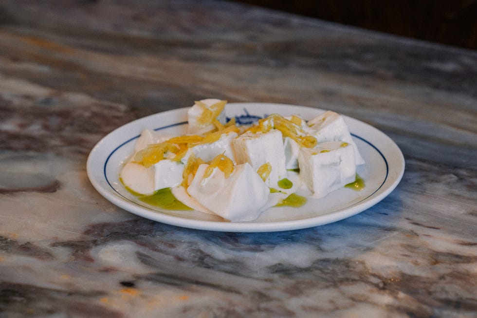 a plate of soft white cheese drizzled with olive oil and garnished with yellow herbs