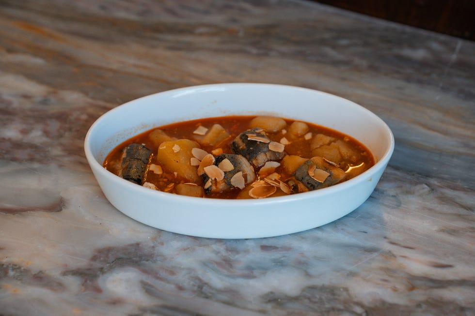 a bowl of stew with pieces of fish and vegetables