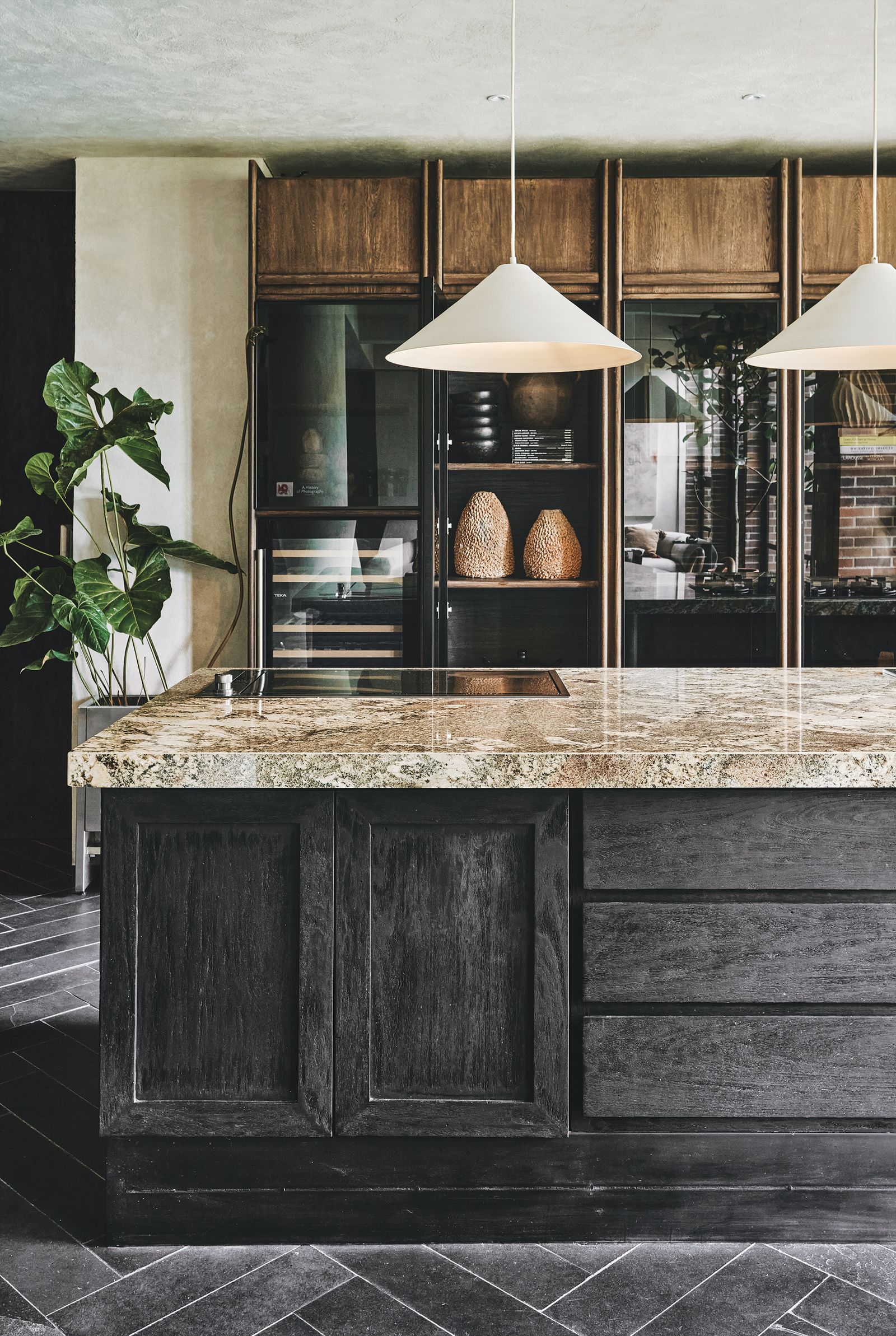 Cocina con piso negro isla de mrmol y vitrina con electrodomsticos expuestos.