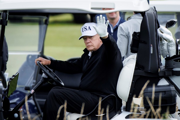 Donald Trump saluda desde el vehículo en el que se mueve por el campo de golf de Turnberry, en Escocia, durante su visita de julio pasado. Foto: EFE