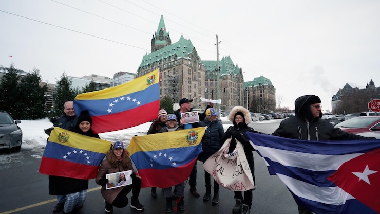 ES: Grupo con banderas de Venezuela y Cuba frente a edificio histórico. FR: Groupe avec drapeaux vénézuéliens et cubains devant un château. EN: Group with Venezuelan and Cuban flags in front of a castle.