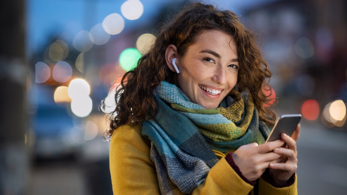 Joven sonriente en la calle usando un teléfono inteligente