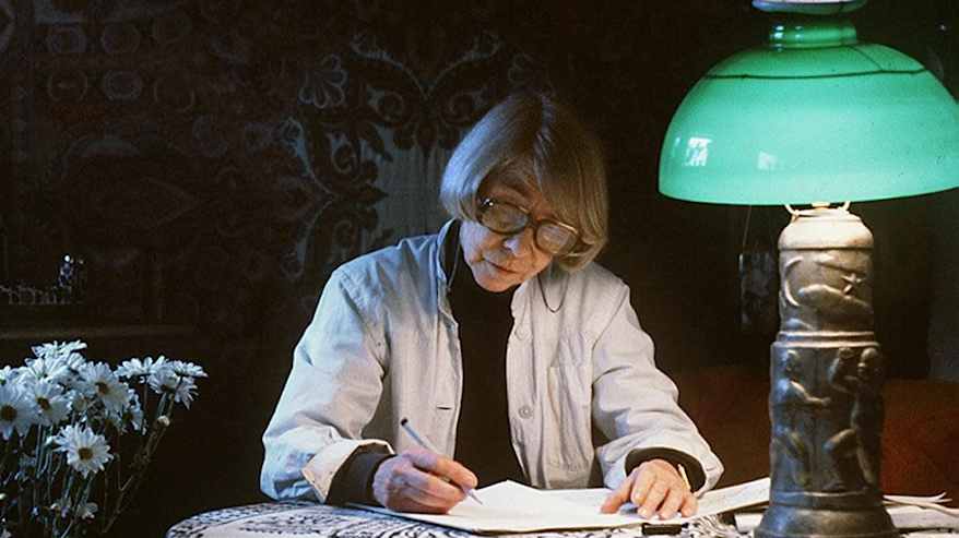 Kirjailija ja taiteilija Tove Jansson kirjoittaa pöydän ääressä.