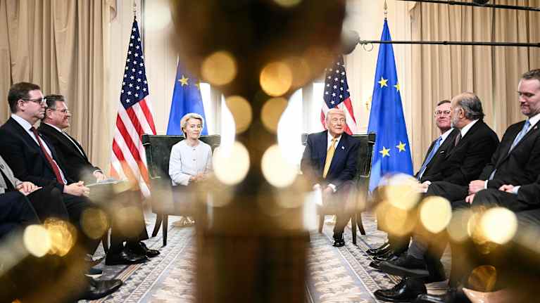  Ursula von der Leyen ja Donald trump istuvat EU:n ja Yhdysvaltojen lippujen edessä.