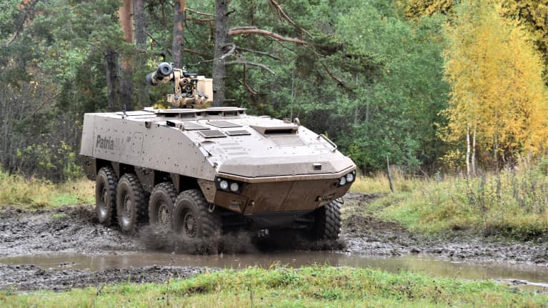 Patria AMV XP 8x8 panssaroitu pyöräajoneuvo syksyisessä, kuraisessa maastossa. Taustalla metsää.