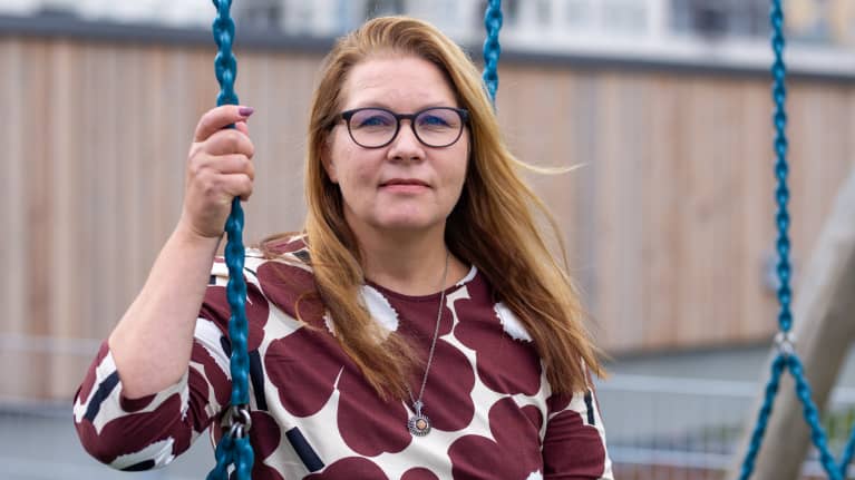 Miia Kemppi istuu keinussa ruskea-valkoisessa paidassa.