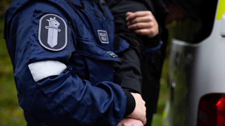 Poliisi pitää kiinni kiinniotetun henkilön kädestä poliisiammattikorkeakoulun poliisiopiskelijoiden rikospaikkaharjoituksessa.
