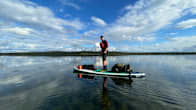Mikko Peltola seisoo vaellusta varten lastatulla sup-laudalla Inarijärvellä.