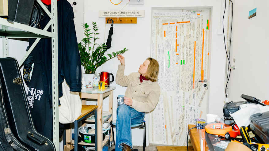 Väinö Karjalainen istuu varastossa ja koskettaa viherkasvia.