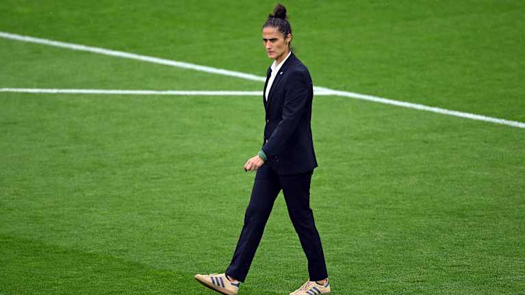 Jalkapallovalmentaja Montse Tome astelee pelikentällä ennen EM-finaalia puvussaan.