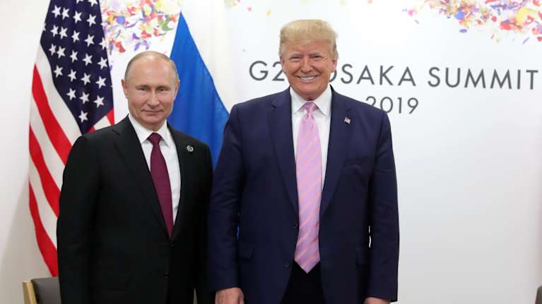 Trump ja Putin seisovat ja poseeraavat kameroille. 