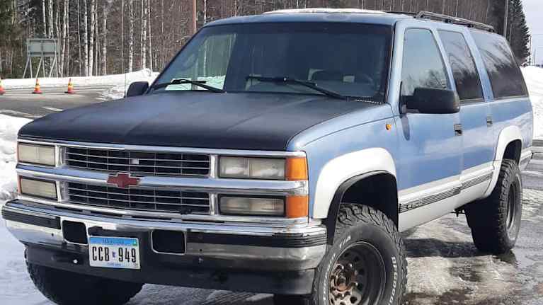 Siniharmaa Chevrolet Suburban aurinkoisena talvipäivänä.