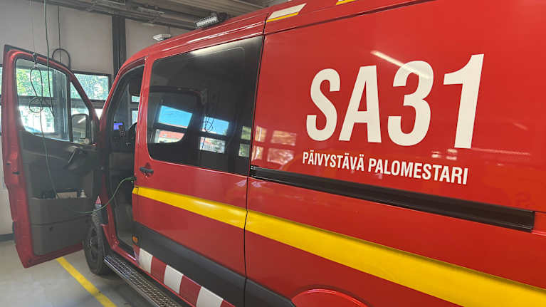 Pelastuslaitoksen yksikön ajoneuvo parkkeerattuna halliin.