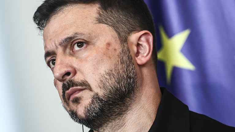 Volodymyr Zelenskyi tiedotustilaisuudessa taustalla näkyy hieman EU-lippua.