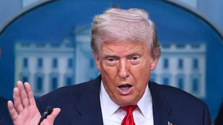 Presidentti Donald Trump puhuu Valkoisen talon logo taustalla.