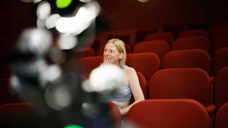 Vega Adsten istuu teatterin katsomossa.