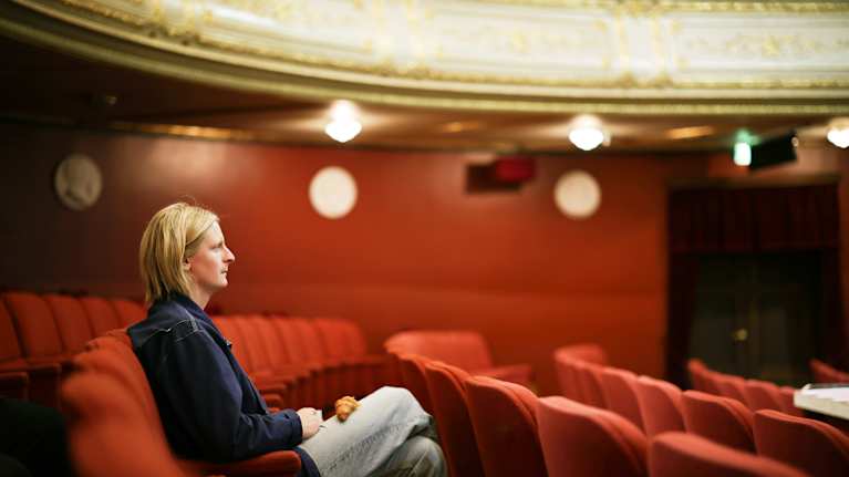Vega Adsten istuu teatterin katsomossa.