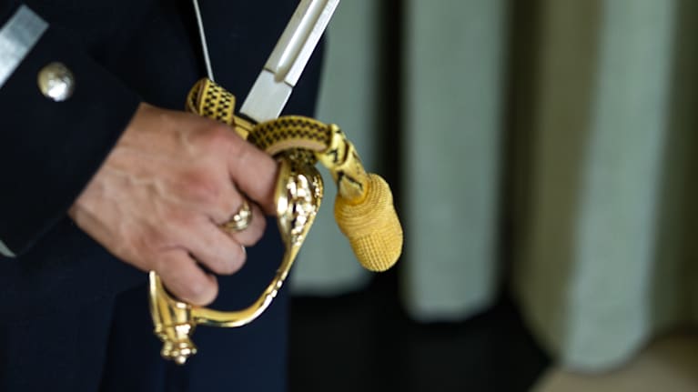 Metallinen miekka upseeriksi valmistuvan kadetin kädessä. 