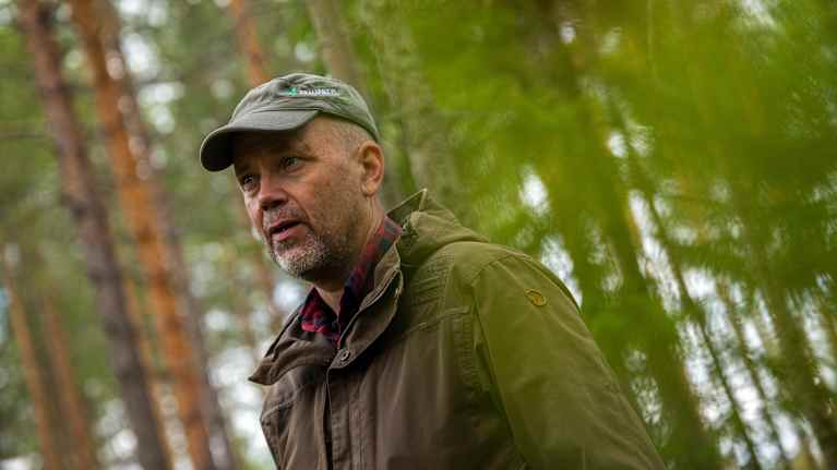 Kai-Eerik Nyholm puhuu toimittajan kanssa metsässä.