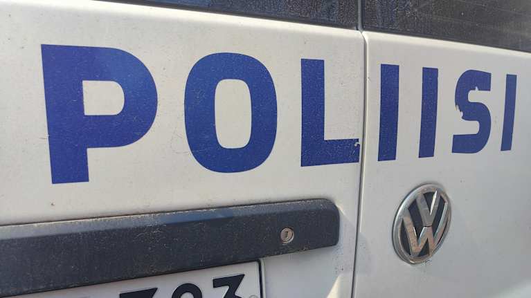 Osittainen näkymä poliisiauton kyljestä, jossa näkyy teksti POLIISI sekä osa rekisterikilvestä.
