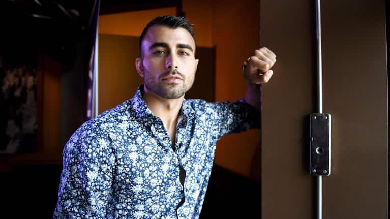 Makwan Amirkhani nojaa kädellään seinään ja katsoo kohti.