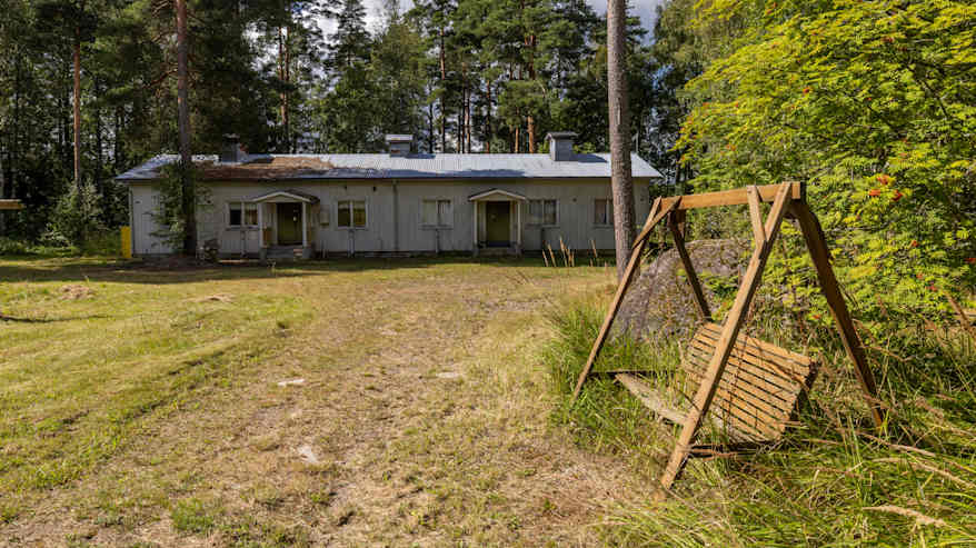 Keinutuoli ja vanha rakennus entisen leirikeskuksen alueella Suur-Miehikkälässä.