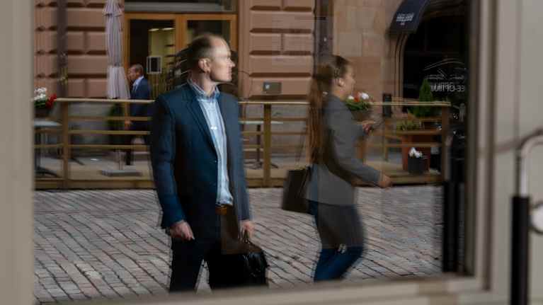 Marko Uotinen kuvattuna kadulla ikkunanheijastuman kautta.