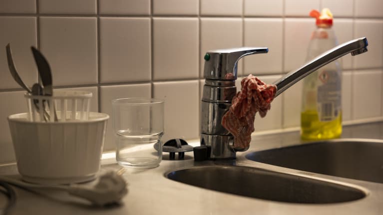 Vesihana, tiskirätti ja aterimien kuivausteline lähikuvassa.