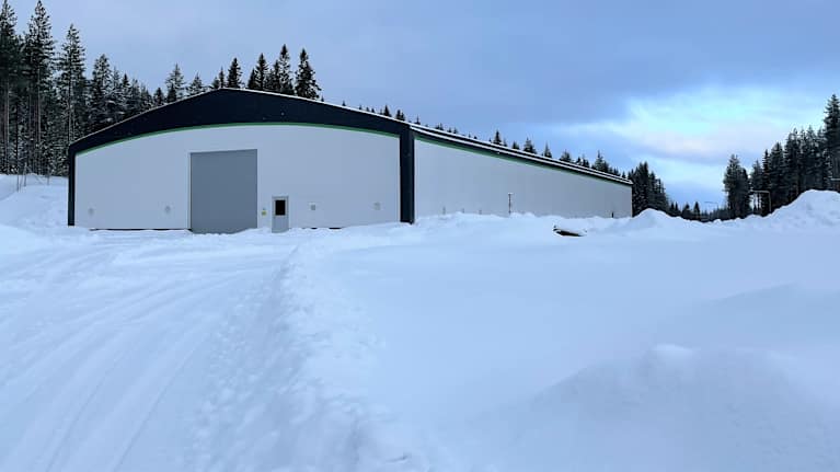 Teollisuushalli seisoo lumisen tontin keskellä.