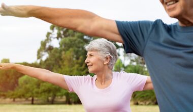 Kuvituskuva. Iäkäs nainen ja mies jumppaamassa puistossa. Ulkona on aurinkoinen kesäpäivä.