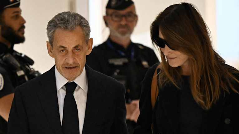 Nicolas Sarkozy kävelee Carla Brunin kanssa oikeustalon käytävällä.