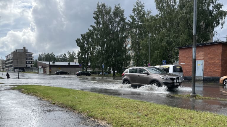Autot liikkuvat kadulla, jolle tulvii vettä.