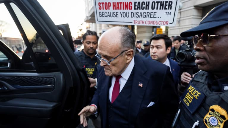 Rudy Giuliani astumassa sisään autoon oikeustalon ulkopuolella, ympärillä väkijoukkoa ja poliiseja.