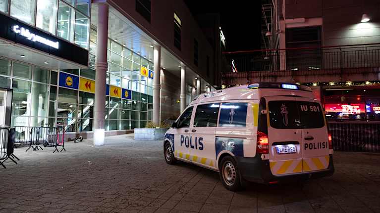 Yön hämärässä Myyrmanni kauppakeskuksen kulmalla seisoo poliisiauto.