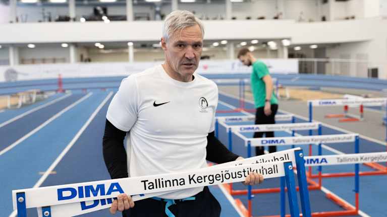 Henkilö harjoittelee sisätiloissa yleisurheiluhallissa ylittäen esteitä.