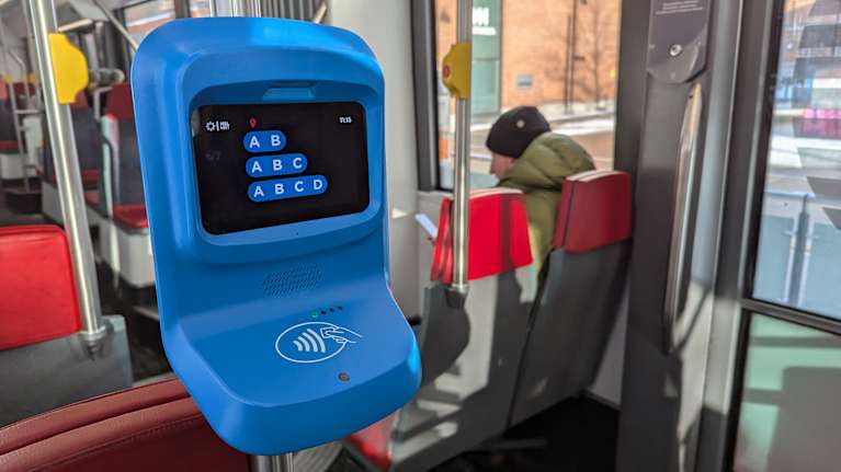 Raitiovaunussa lähikuva sinisestä lipunleimaamislaitteesta.