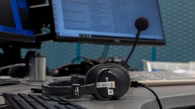 Radiostudion pöydällä kuulokkeet joissa mikrofoni.
