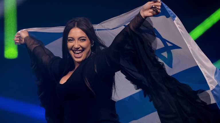 Nainen pitää kädessään Israelin lippua lavalla.