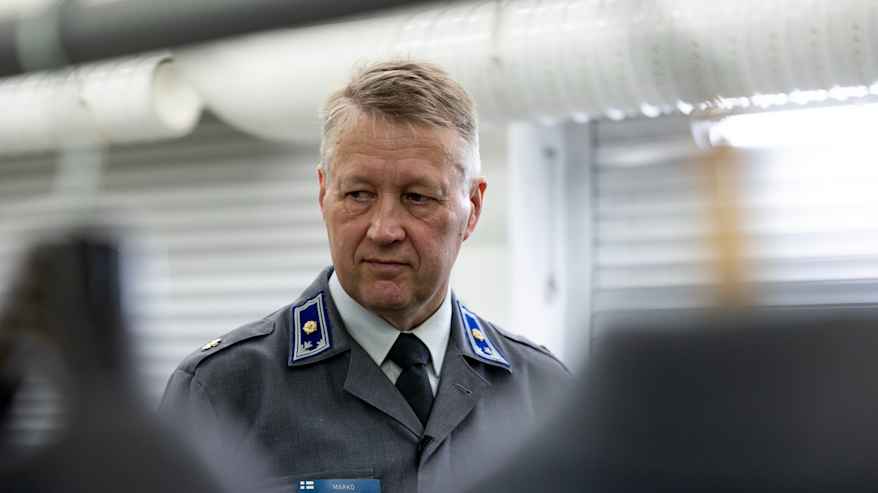 Lähikuvassa armeijan harmaa puku päällä oleva Marko Maaluoto katsoo pukuja. 