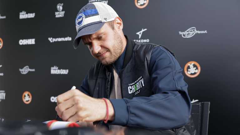 Barkov jakamassa nimikirjoituksia pöydän ääressä. Pöydällä paljon kiekkoja.